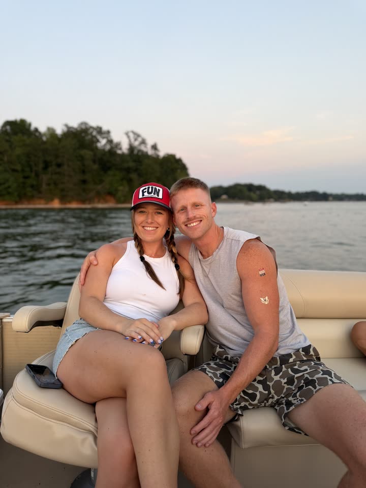 Zach von der Linden sitting with a woman on a boat on a lake at sunset, with trees along the shore behind them